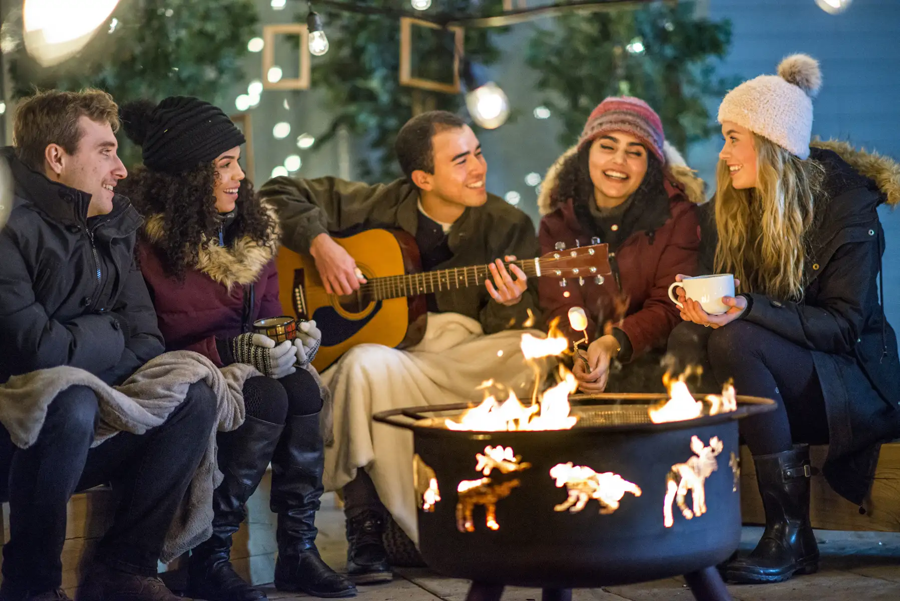 friends with guitar sitting around fire pit